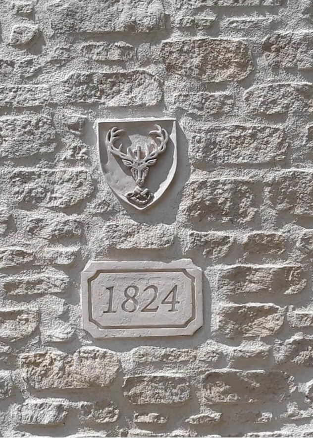 blason à la tête de cerf sculpté dans un enduit de façade à la chaux avec finitions effet pierre